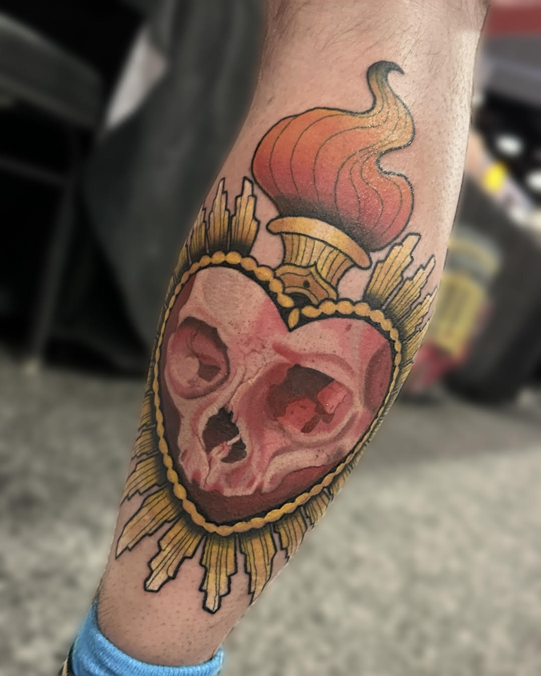 Traditional sacred heart skull with flames and gold frame tattoo