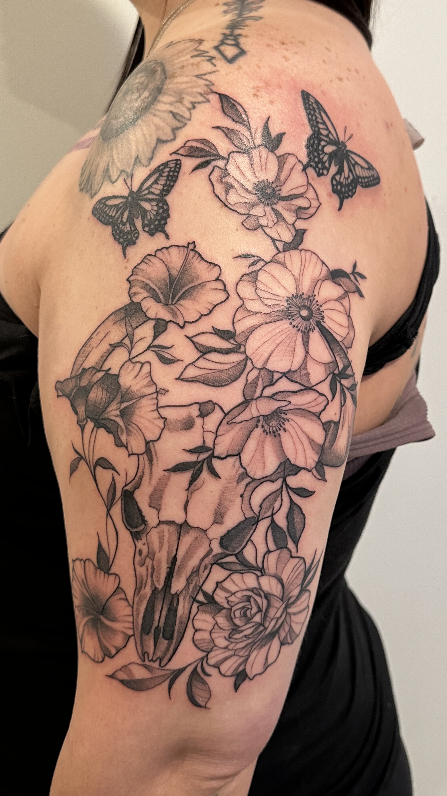 Black and grey animal skull with flowers and butterflies half sleeve tattoo