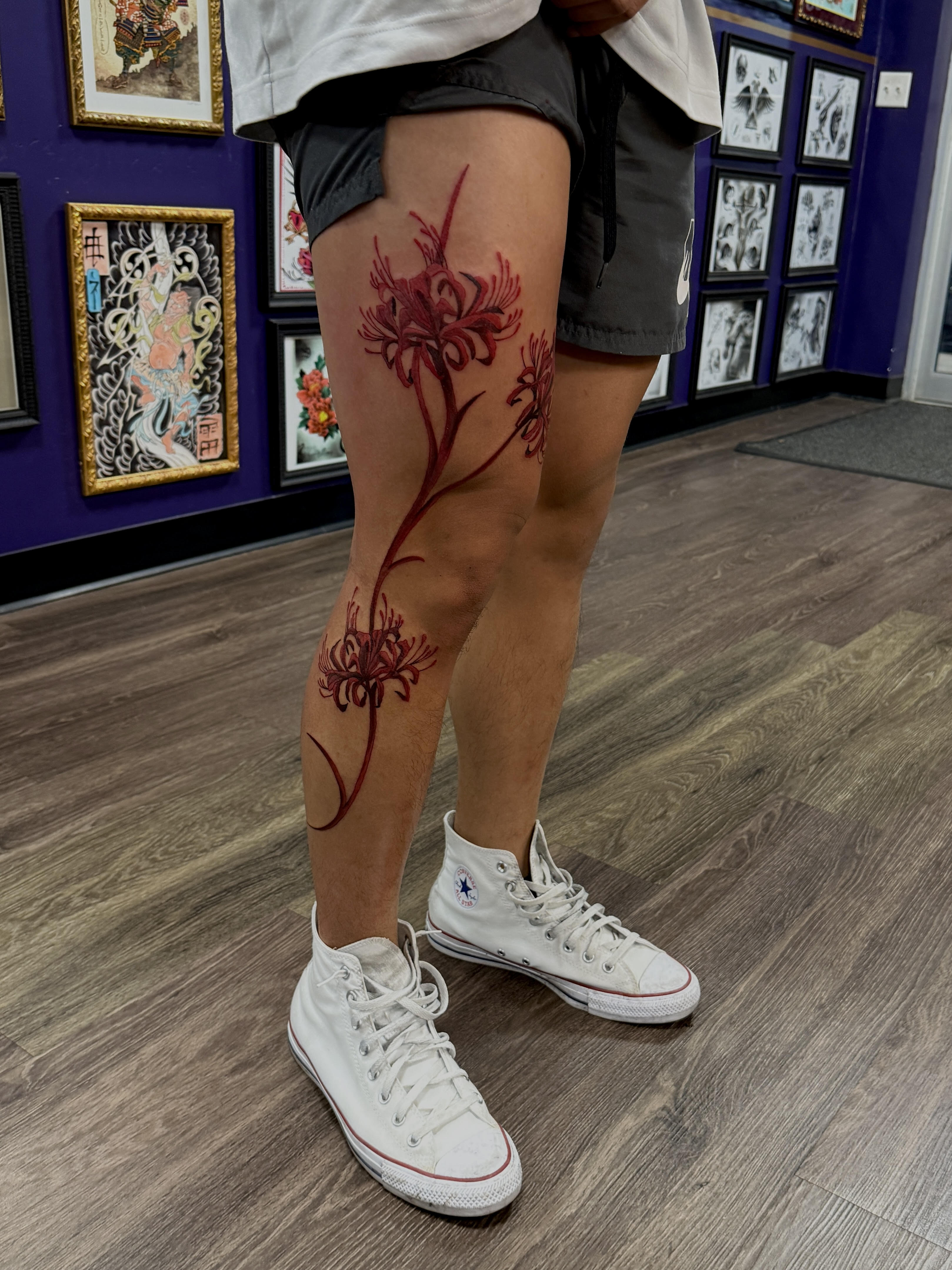 Fine line red spider lily thigh tattoo